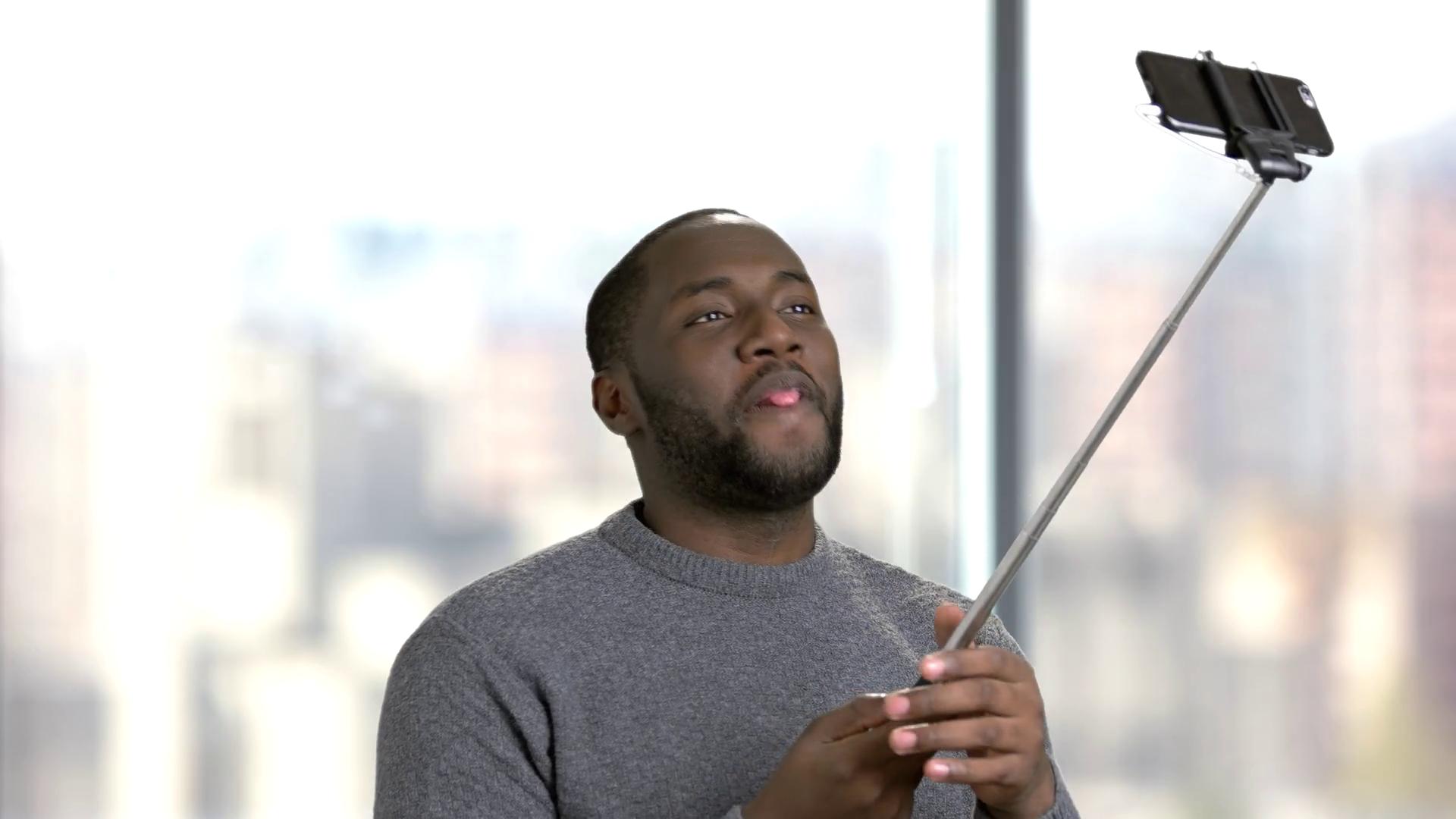 Young black man using selfie stick. Cheerful afroamerican guy having