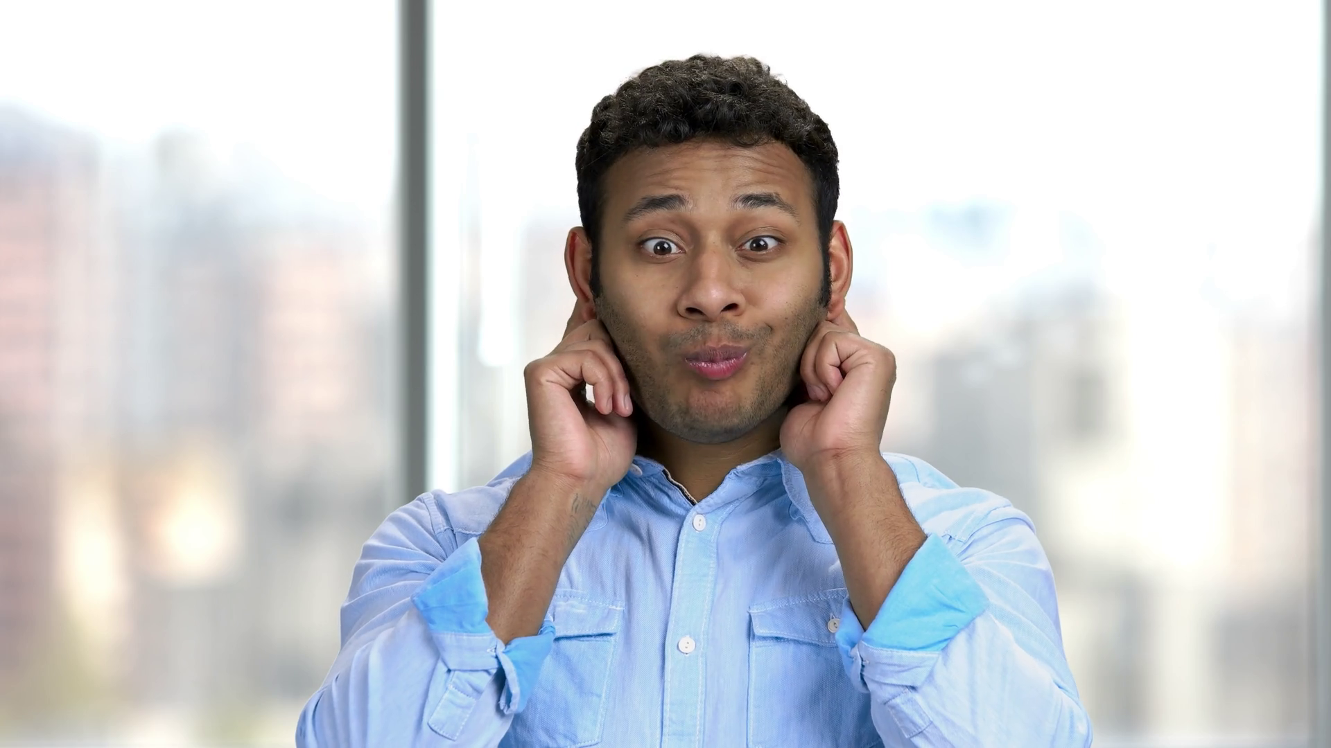 Young Indian man grimacing on blurred background. Portrait of guy
