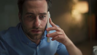 Pensive man talking by phone in office