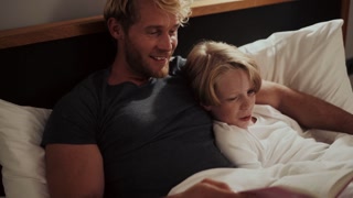 Positive father reading a story to his son in bed