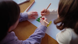 Teenage girls draw Christmas tree out of plasticine on paper at library