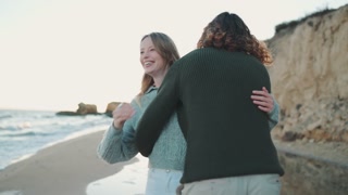 Back view of friendly couple running and hugging on beach
