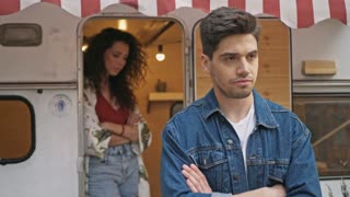 Sad young offended couple having a quarrel while standing near the trailer