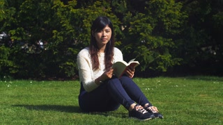 Beautiful woman reading a book in the park. 4K video