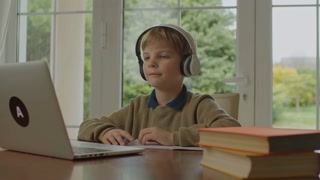 Young student learning online at home, happily engaged with laptop