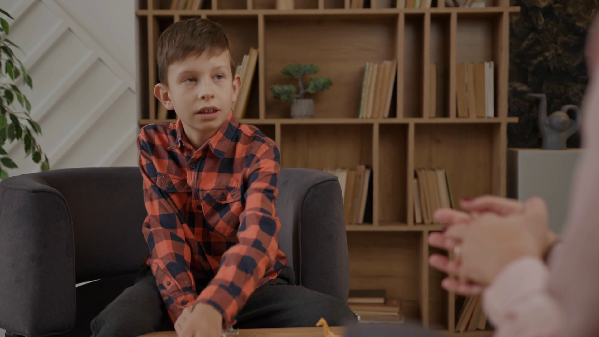 Autistic kid making therapist assignments sitting in psychologist office. School boy with autism