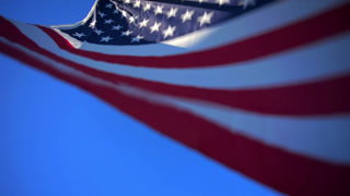 USA Flag Waving Against Clear Blue Sky with Stars and Stripes in Motion.