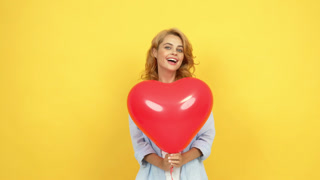 happy woman blow kiss and wink behind heart party balloon,
