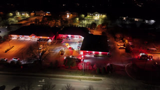 Aerial view of an emergency scene with police cars and fire trucks with flashing red lights at night