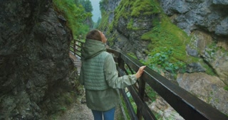 Woman hiking in mountains  in Austria. Girl looking up in a Dark Gorge and enjoying calm rainy day in nature.