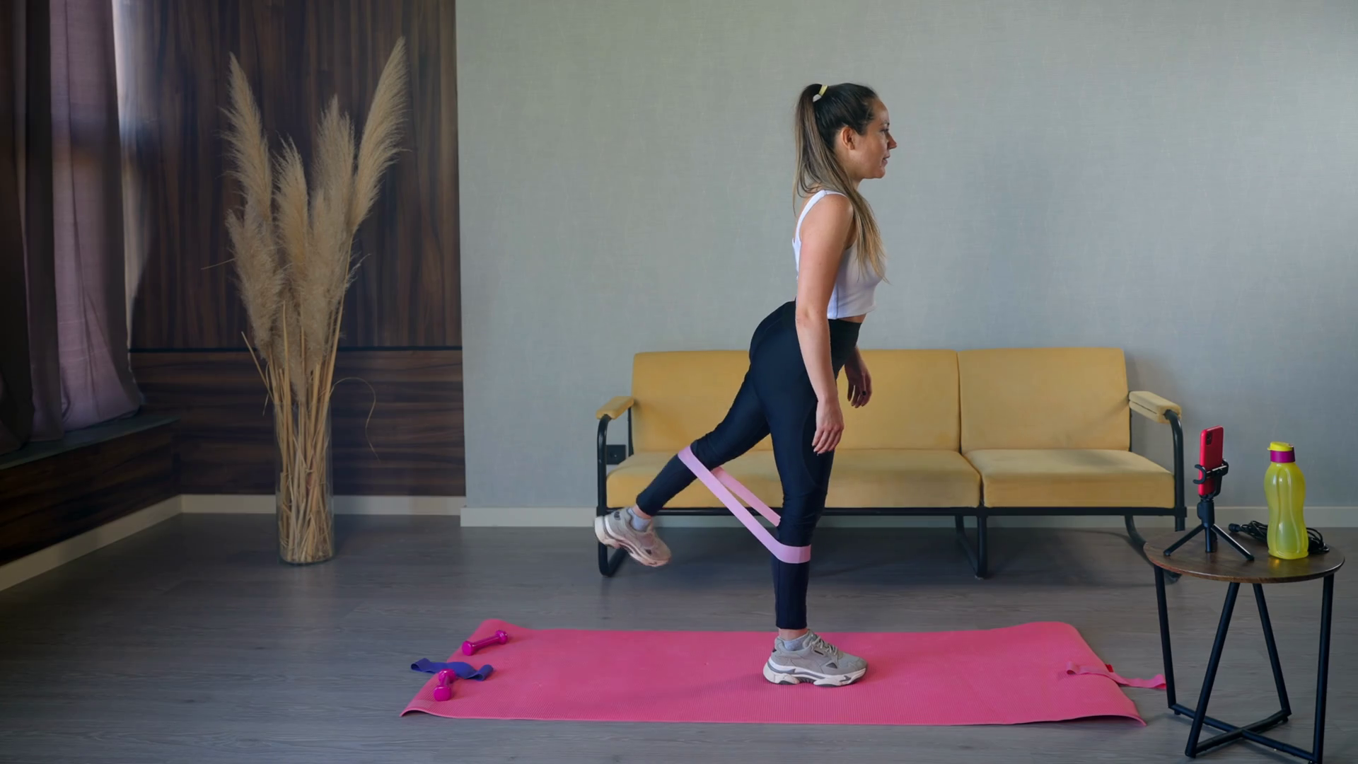 Fitness at home. Young woman doing standing glute kickbacks with