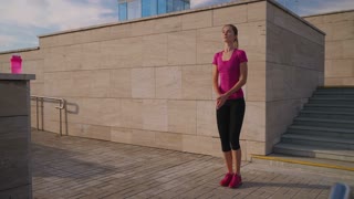 Fit woman doing morning exercises and performing jumping jacks. Cardio workout outdoors