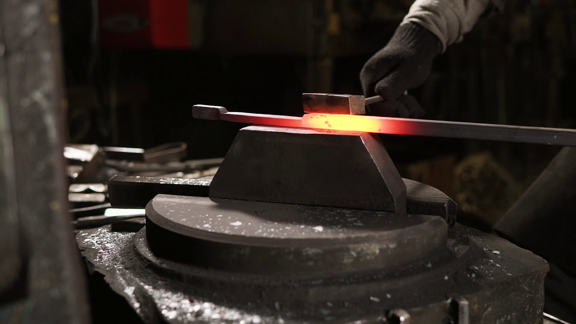 Blacksmith is using hammer machine for shaping metal blank. He is