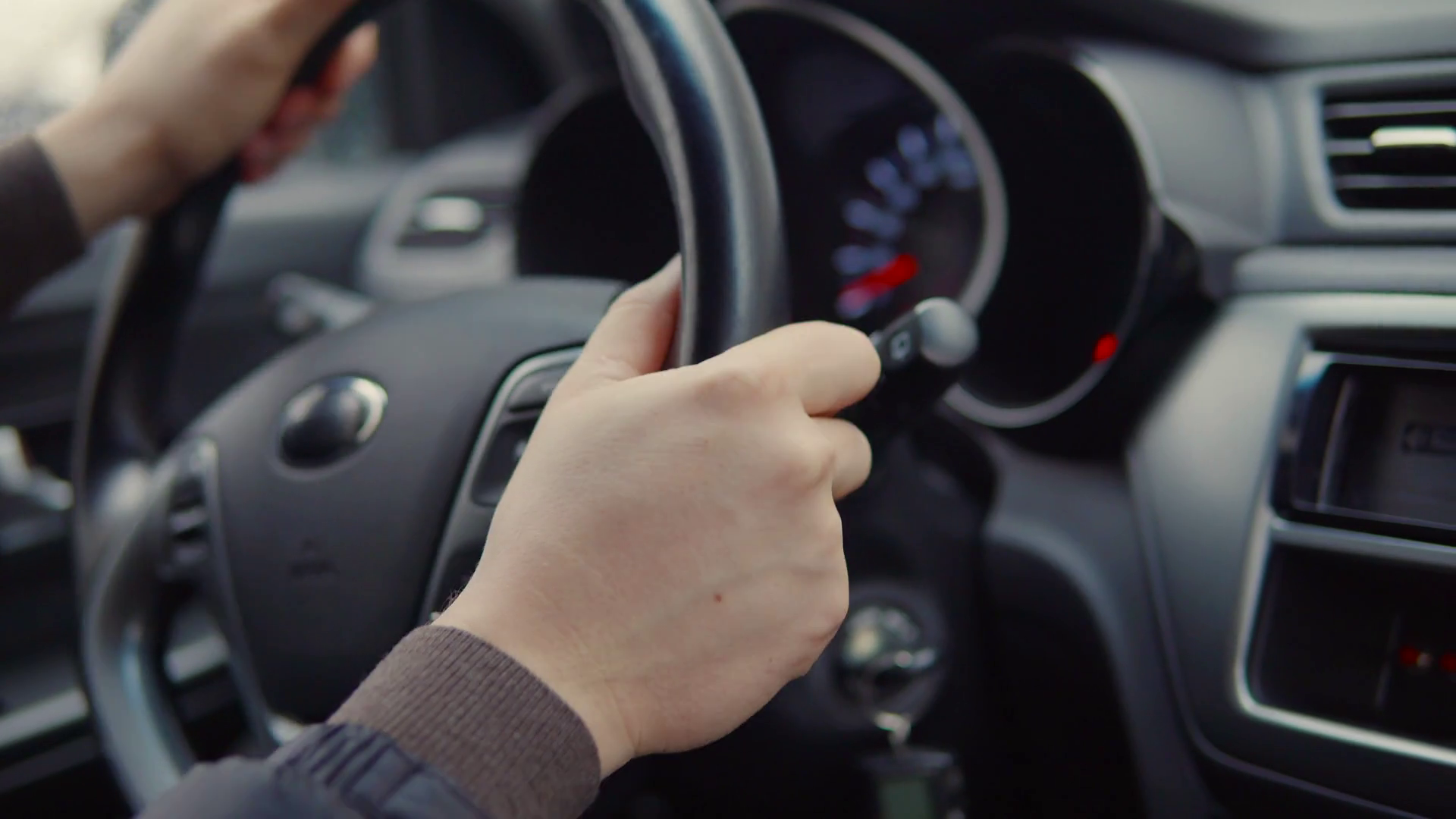 Male hands are turning steering wheel of modern automobile, closeup