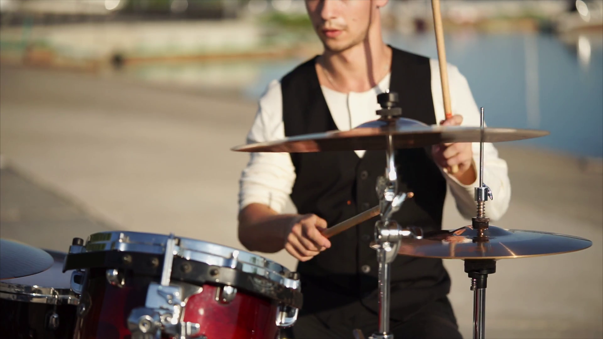 Slow motion shot of a man playing music on drums during outdoor musical