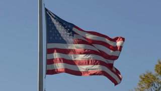 Waving American Flag Against Clear Blue Sky. Memorial Day, Veterans Day, 4th of July, Patriotic USA Holiday. American Flag Flapping in Wind Blue Sky. American Flag Symbol of Freedom and Democracy.