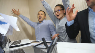 Young business people celebrating achievement throwing up documents and showing joyful emotions. Office workers rejoicing success after hard