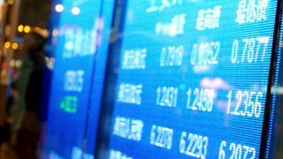Close up view of a blue digital stock market exchange board showing real time financial data and currency trading numbers online