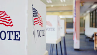 Row of white voting booths with American flag and vote text inside a polling station during a government election in America