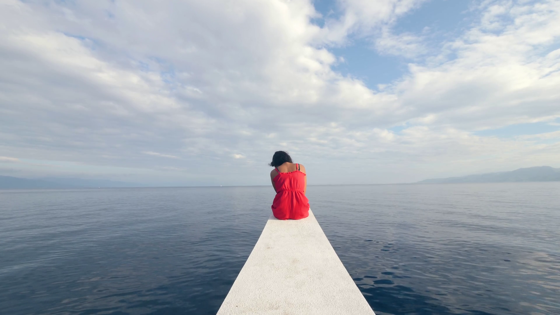 Back view of a sad young woman sitting alone on the edge of the boat