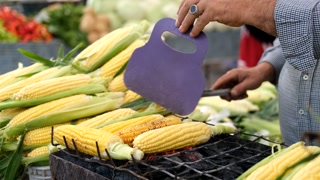 close-up of a man preparing corn on the grill