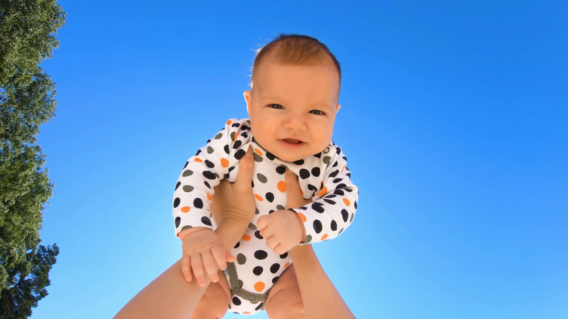 Mother throwing baby up against the blue sky. Happy woman enjoying