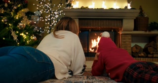 Woman with child boy laying on floor in front of fireplace and Christmas tree