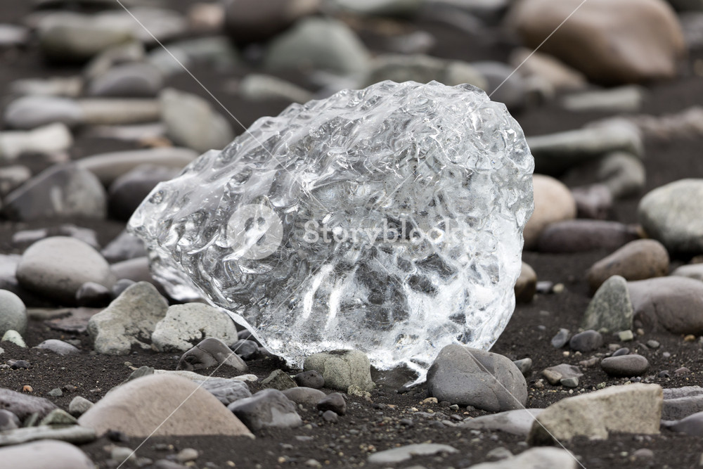 Close up of a piece of ice among pebbles RoyaltyFree Stock Image