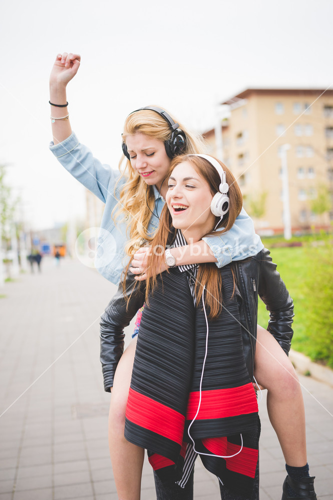 Two young friends enjoying music and friendship in the city