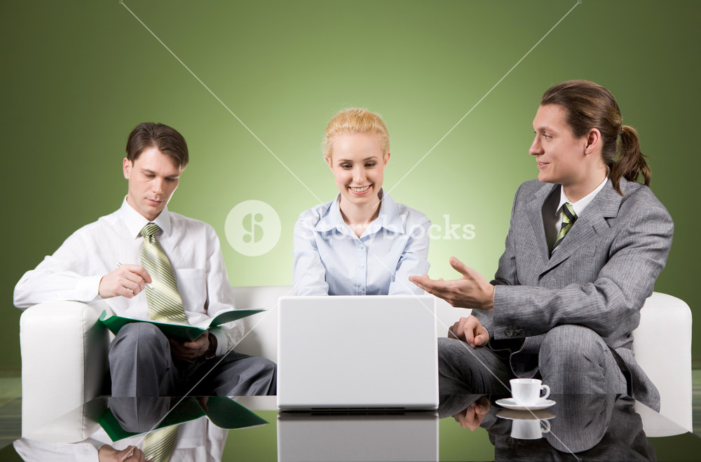 Portrait of businesspartners communicating at meeting with their colleague sitting near by