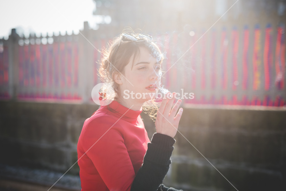 Stylish woman in vintage attire at the station, enjoying a cigarette