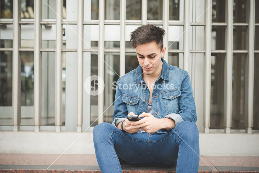 young stylish model man in urban area using smartphone